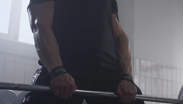 mand holder vægtstang med straps om håndledene